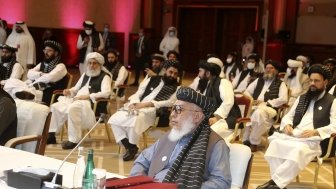 The Taliban negotiator sits at a table with his delegation behind him at the peace talks in Doha, Qatar.