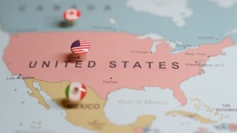 US flag push pin marking the United States on a map, with Mexico and Canada location pins visible. High quality photo