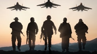 Soldiers walking away from camera with planes overhead