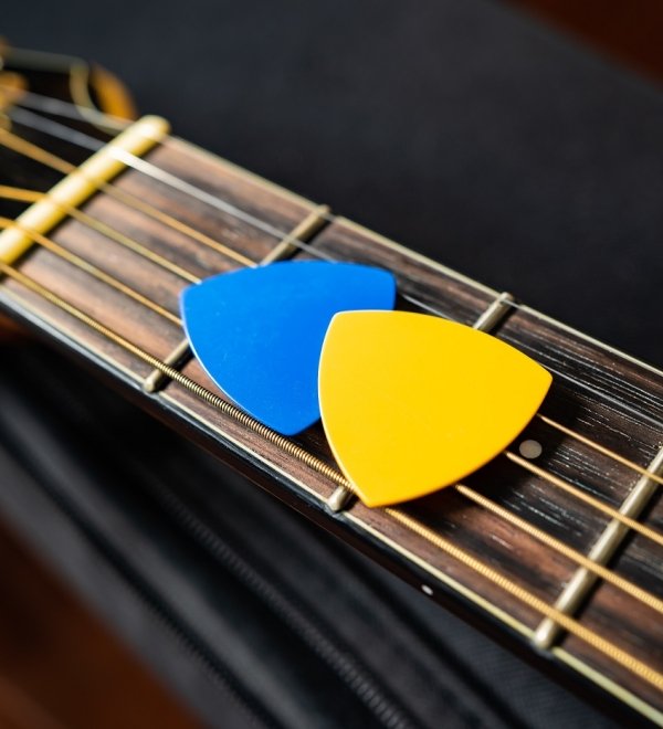 Blue and yellow guitar picks on an acoustic guitar