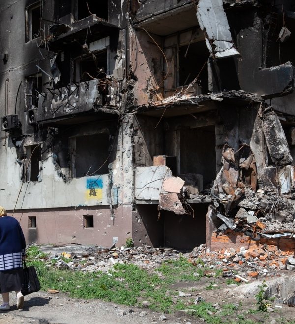 old woman walks past apartment building destroyed by the Russian army as a result of Russia's invasion of Ukraine in Borodianka, Ukraine