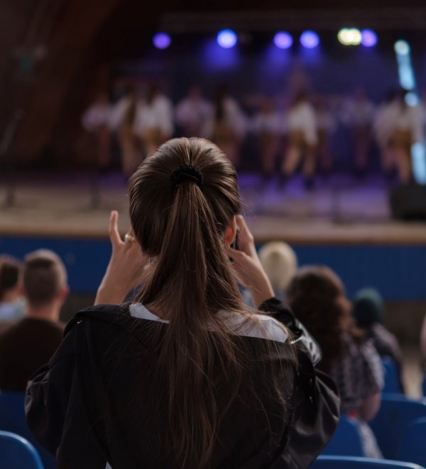 Girl taking a photo of dancers on the stage. 