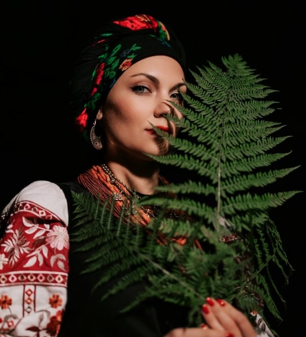 A woman in traditional Ukrainian handkerchief and vyshyvanka holding a leaf.