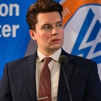 A photo of Lucas Myers speaking at a conference with the Wilson Center logo in the background.