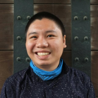 Man smiling in front of door with light blue bandana