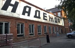 Kathryn David stands in front of a large sign that reads "hope" in Russian