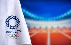 A towel with the logo for the Tokyo 2020 olympics in the foreground with track and field starting blocks in the background in soft focus