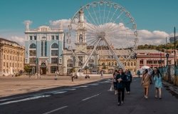 Podil, Kyiv, Ukraine - June 16, 2021 - street shot of people on the main square of the Podil neighborhood with ferris wheel and traditional architecture