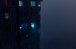 Person shining flashlight from a dark apartment building 
