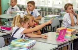 Odessa, Ukraine - September 1, 2015: elementary school students at their desks with textbooks on the first day of the school year. Feast Day of Knowledge. Beginning of a new academic year.